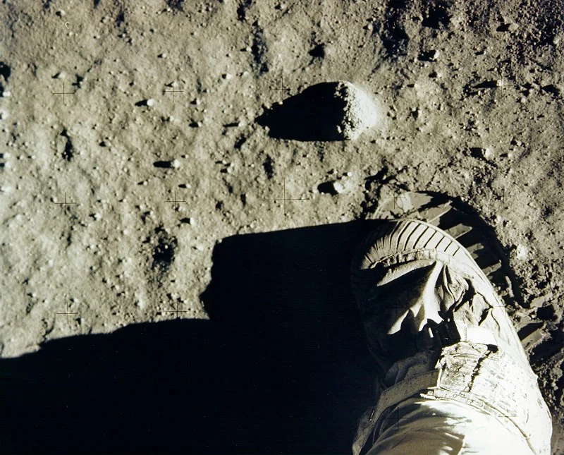 Buzz Aldrin’s boot beside a sharply ridged impression in the fine lunar soil.