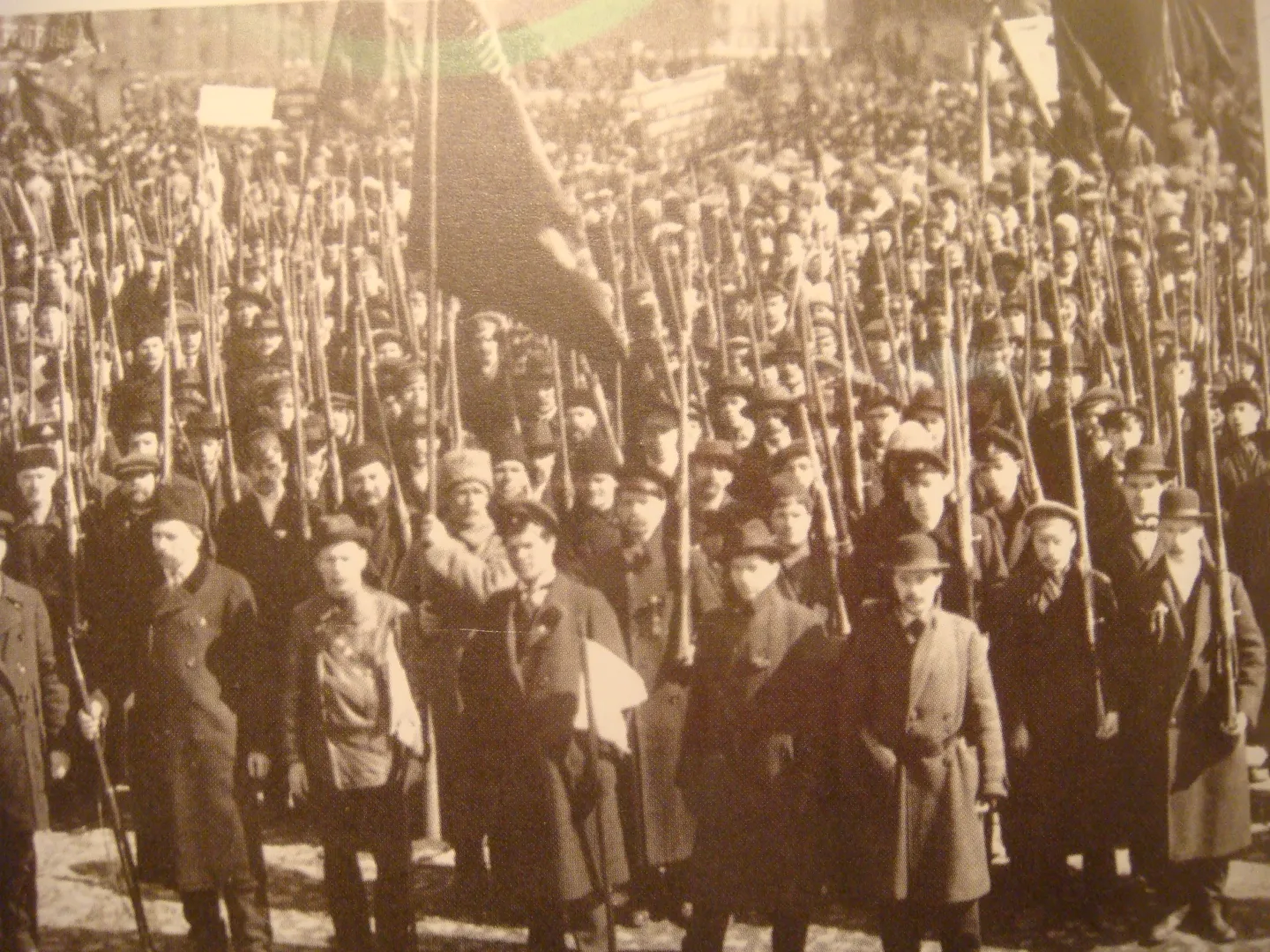An armed Red Guard formation fills a Petrograd street, with rifles among uniforms and civilian clothing.