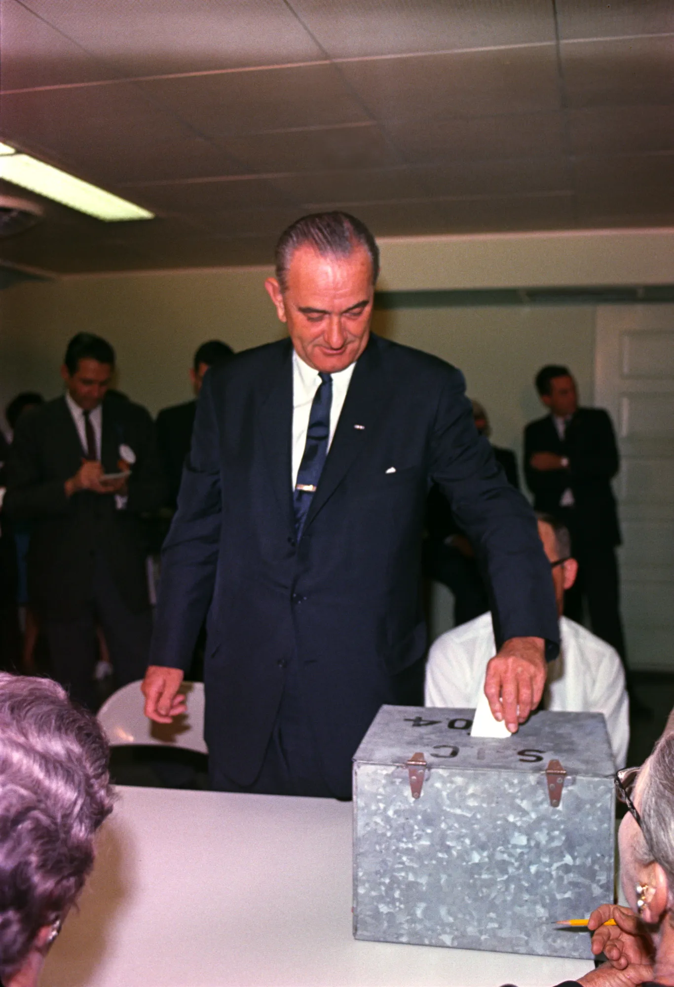 Lyndon Johnson places his ballot into a metal ballot box.