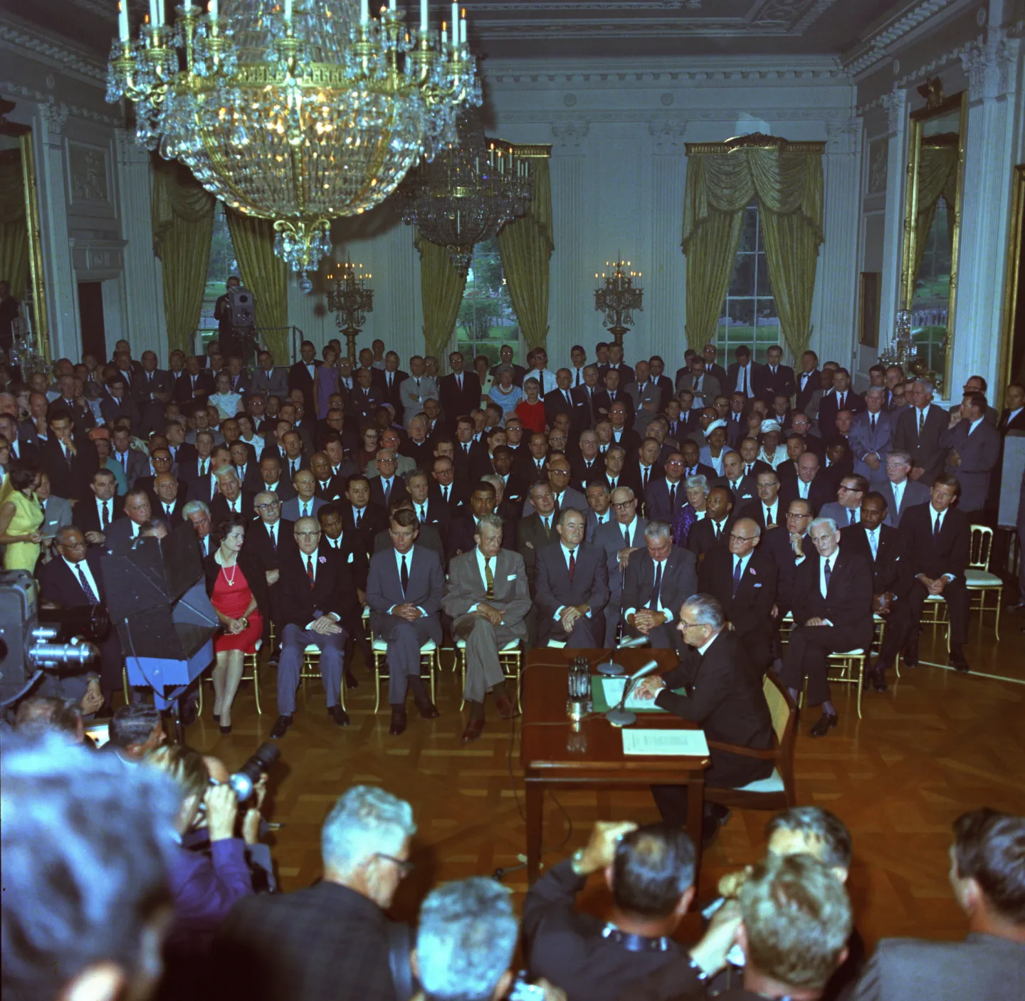 Johnson seated at a signing table before a crowded White House East Room.