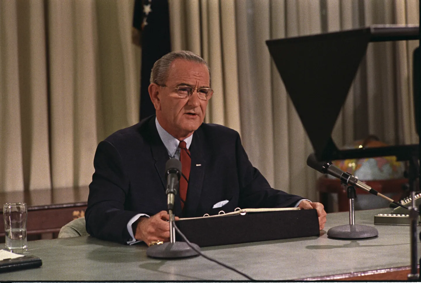 Lyndon Johnson sits at his desk speaking into television microphones on March 31, 1968.