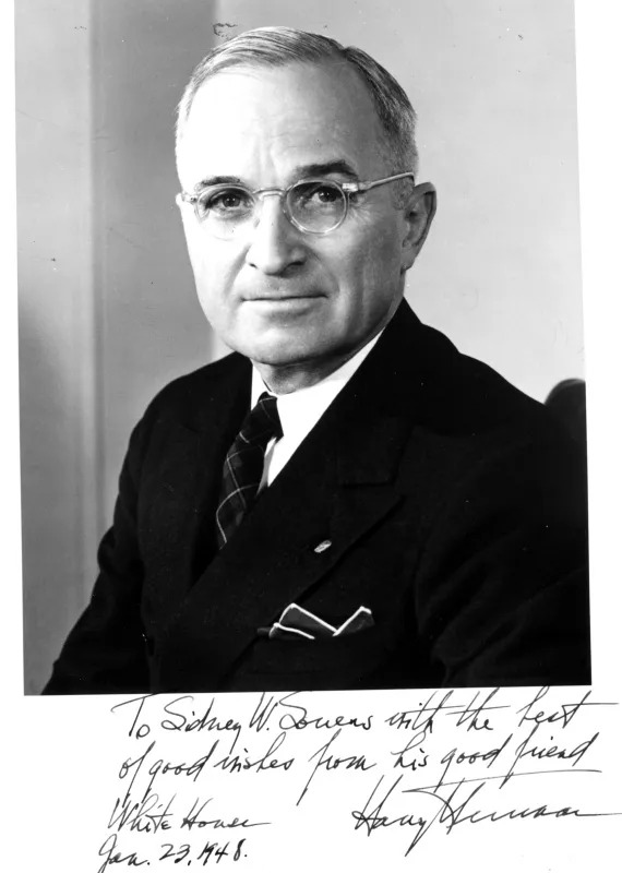 Official portrait of Harry Truman, wearing glasses and a dark suit.