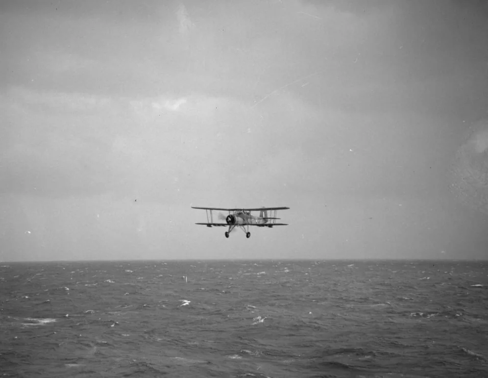 A Fairey Swordfish flying low toward the camera over rough Atlantic water after an attack on Bismarck.