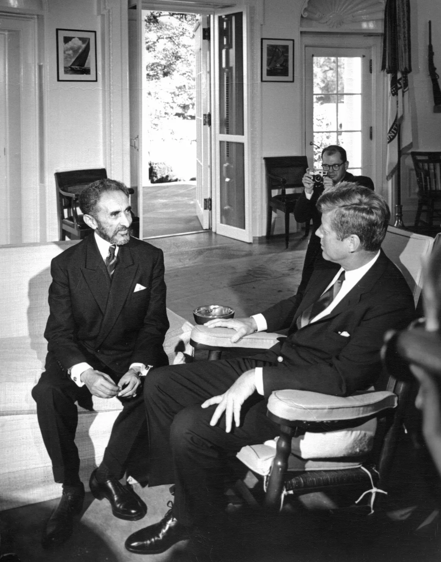 Haile Selassie and John Kennedy seated in conversation in the Oval Office.