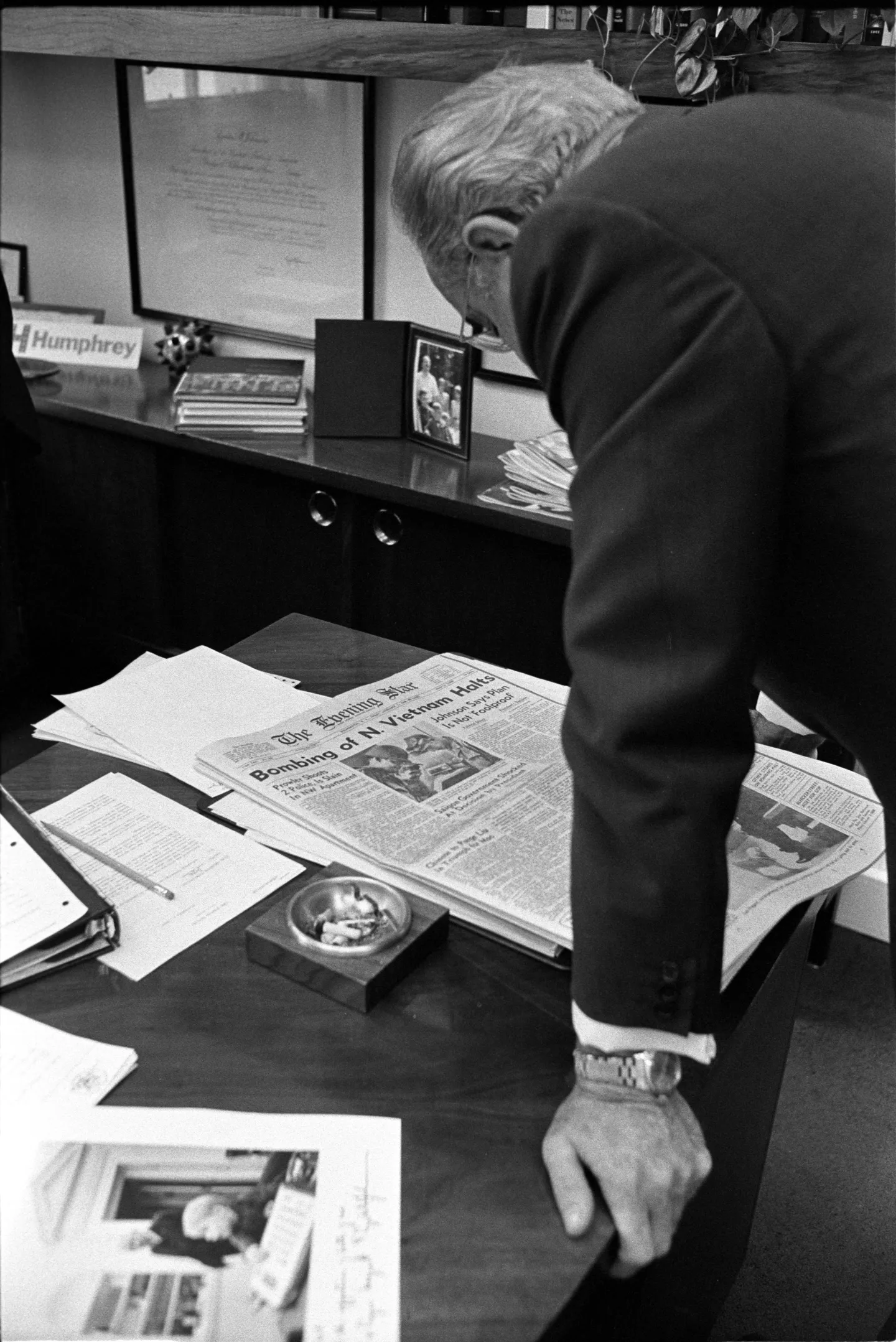 Johnson reads a newspaper bearing a headline about the halt to bombing North Vietnam.