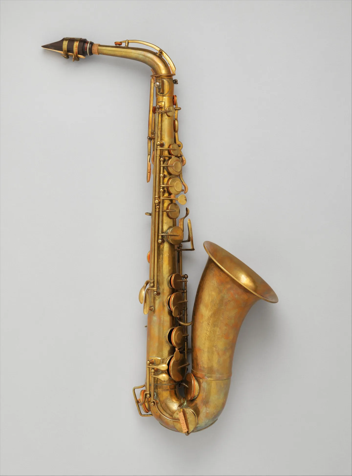 Early brass alto saxophone with curved bell and exposed key mechanisms.