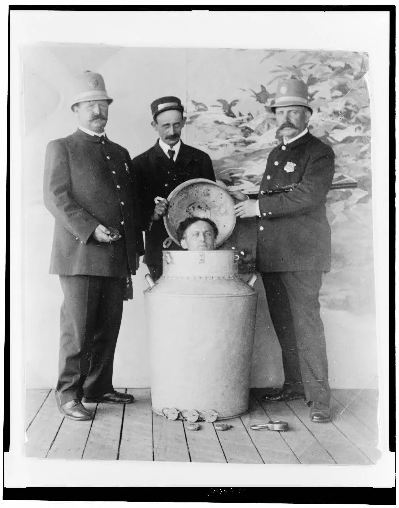 Houdini and assistants pose around the giant milk can used in his escape act.