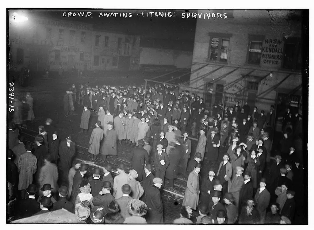 A large crowd gathered in a brightly lit New York street while awaiting Titanic survivors.