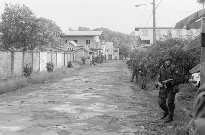 U.S. Marines carrying rifles patrol a street in Grenville on Grenada during the 1983 invasion