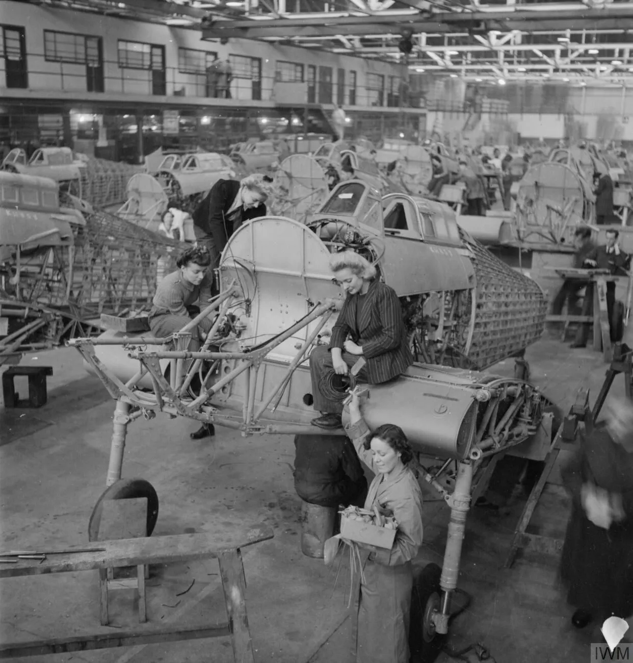 Women working around the open structure of a Hurricane on an assembly line.