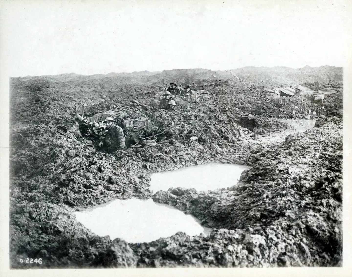 Canadian soldiers and a machine gun in muddy shell-hole positions.