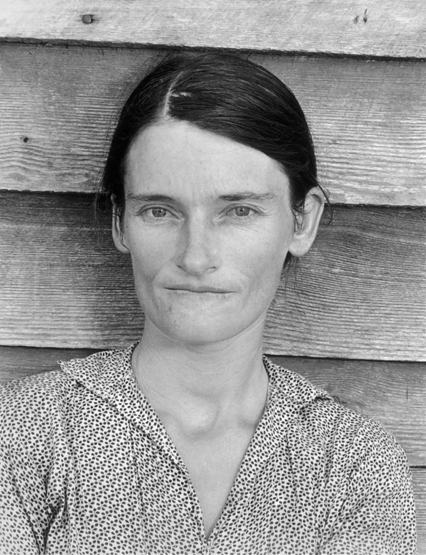 Allie Mae Burroughs faces the camera against a wooden wall.