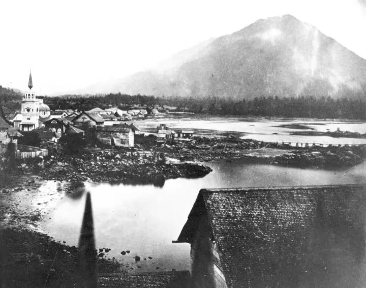 An 1868 view of Sitka from the Governor’s Garden, with St. Michael’s Cathedral and a mountain behind the town.