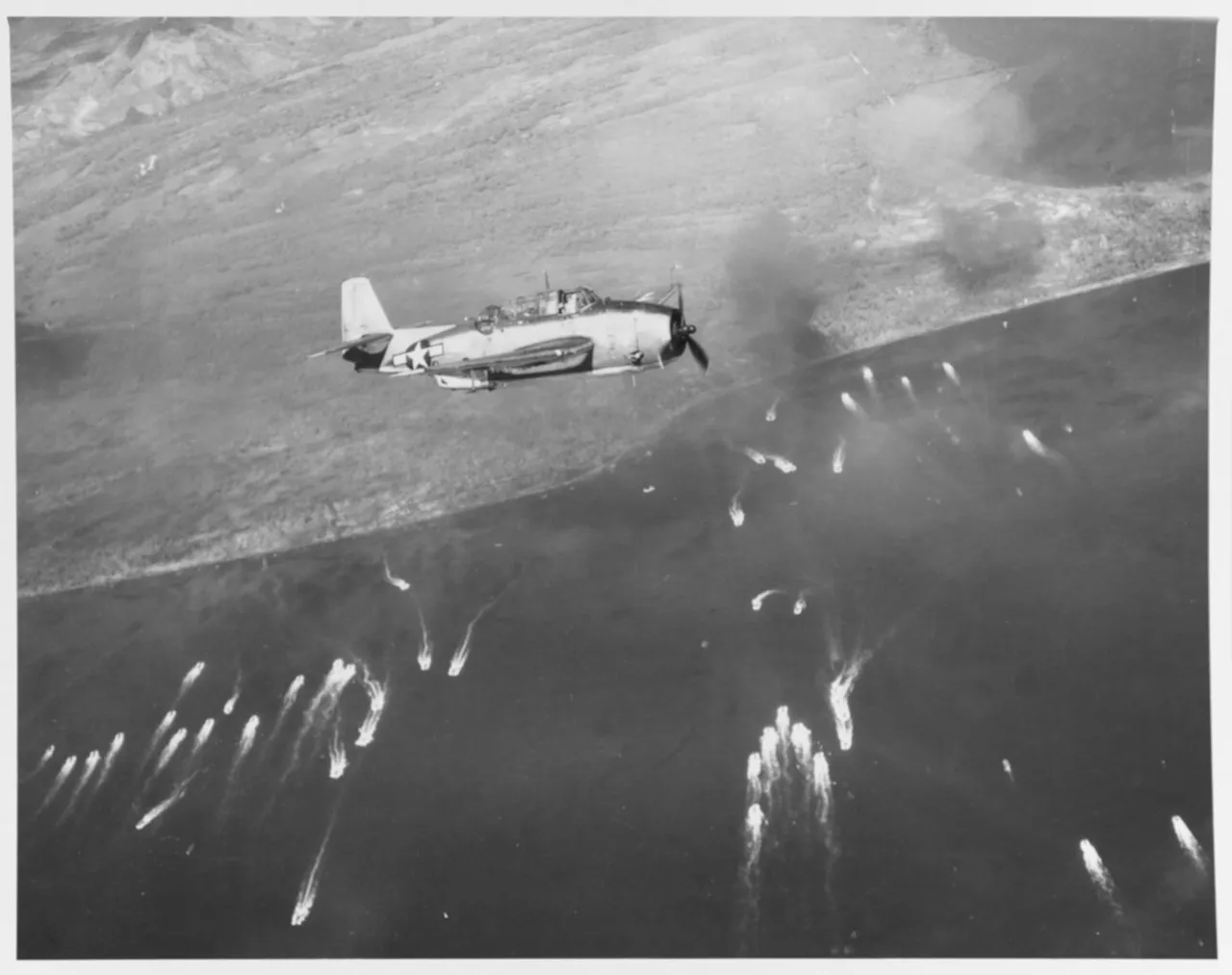 A Grumman Avenger flying over landing craft approaching the beaches near Tacloban on Leyte.