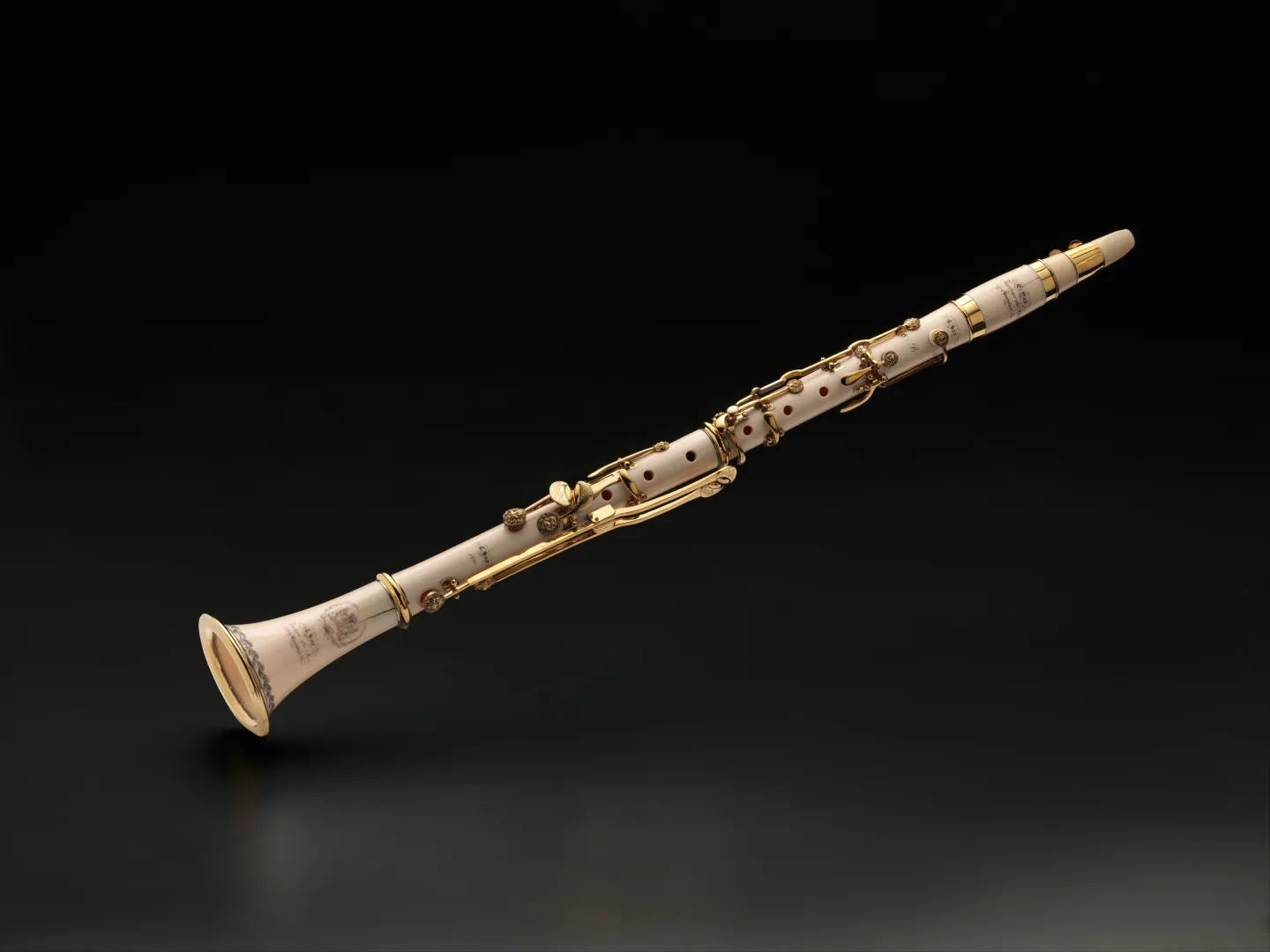 White ivory clarinet with gold-colored keys lying diagonally against a dark background.
