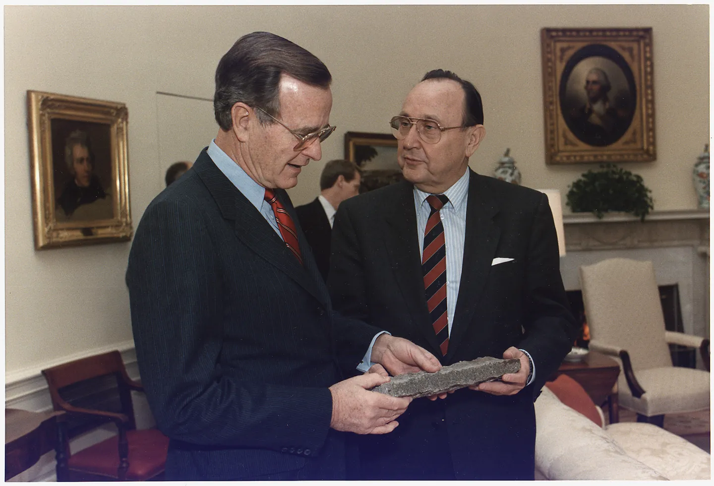 George H. W. Bush receiving a piece of the Berlin Wall from Hans-Dietrich Genscher in the Oval Office.