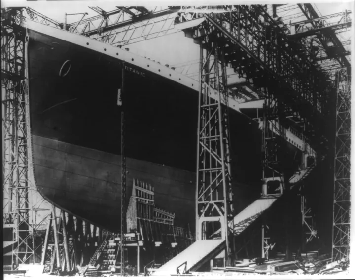 Titanic’s high bow and hull surrounded by steel scaffolding in the shipyard.