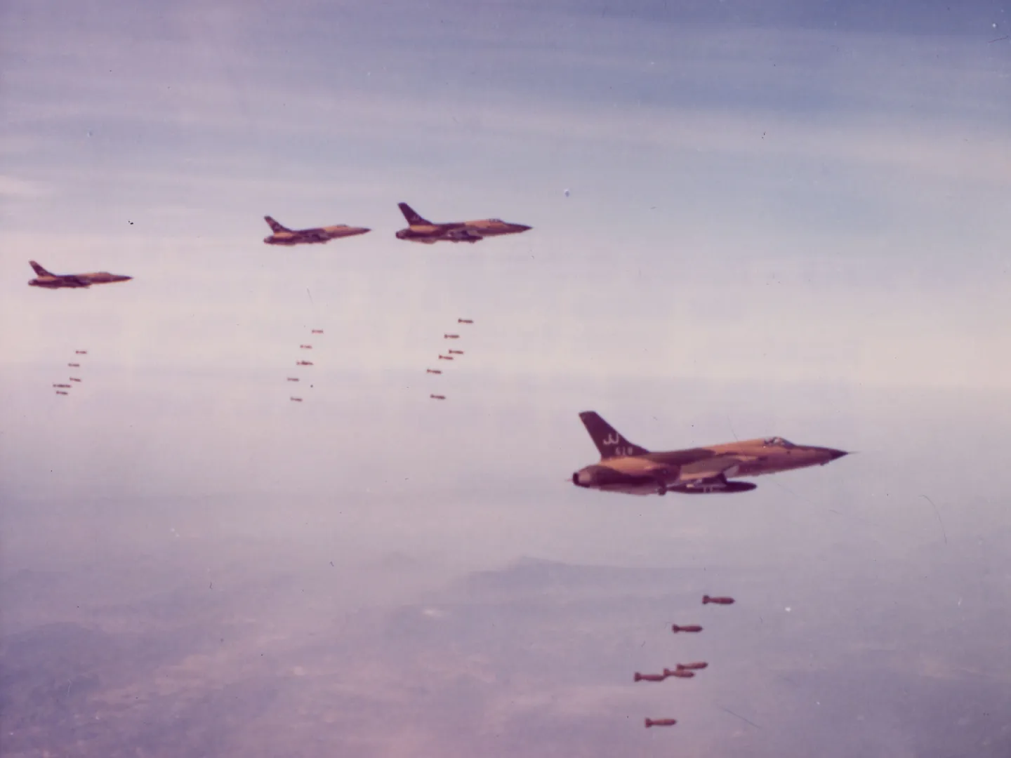 Four F-105 aircraft release bombs over Vietnam.
