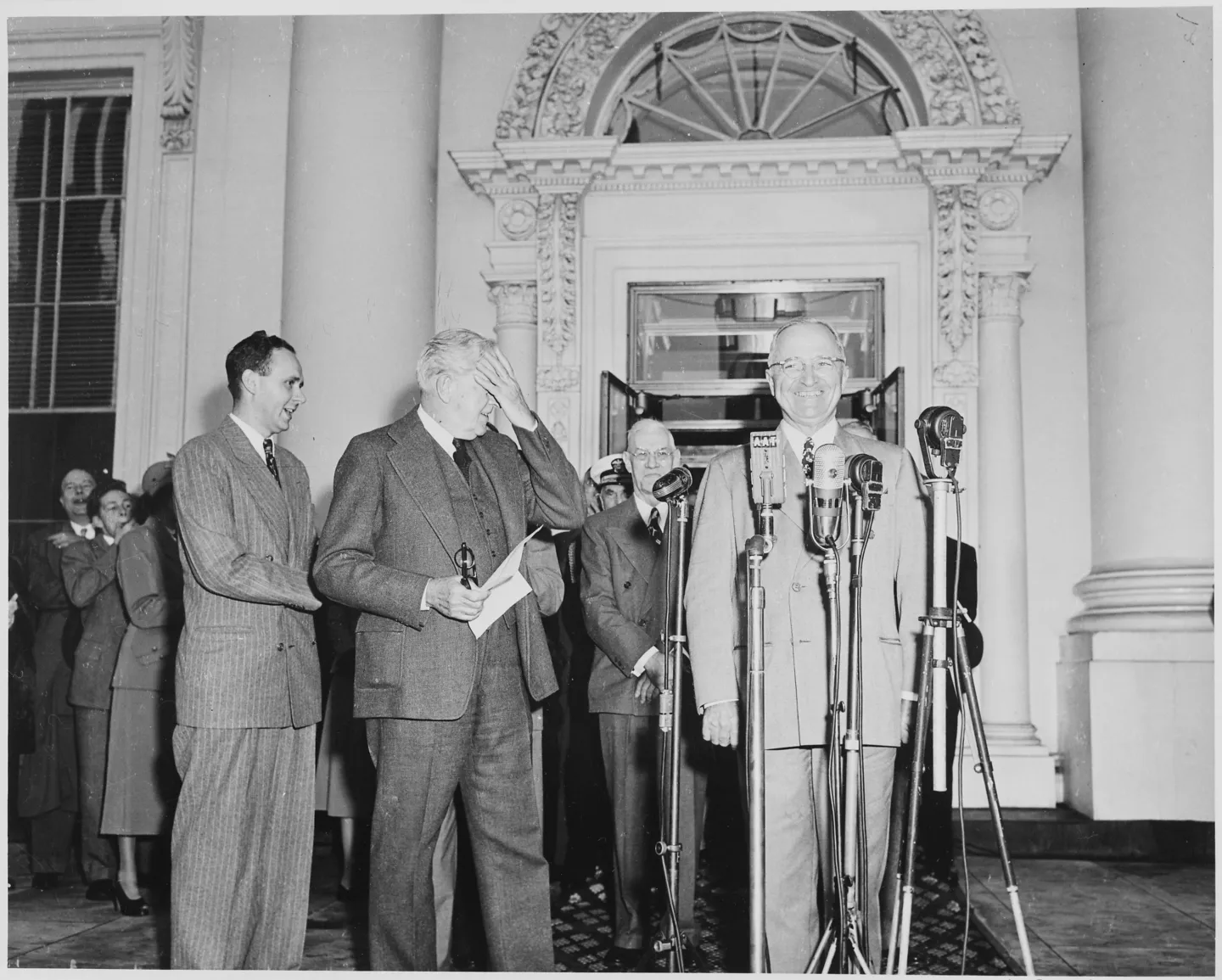 Truman standing at microphones on the White House porch with Barkley and a group of supporters.