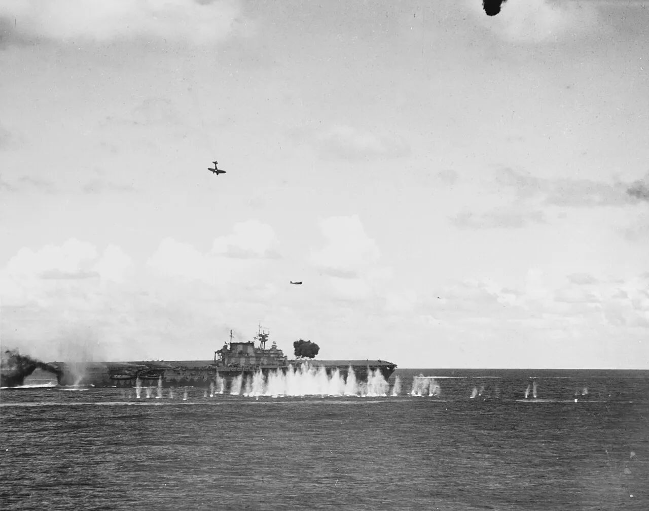 Japanese aircraft attacking USS Hornet, with a smoke-trailing dive bomber above the carrier on October 26, 1942.
