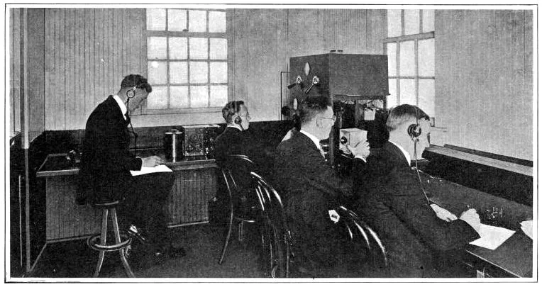 Men at a microphone and receiving equipment in an early KDKA room.