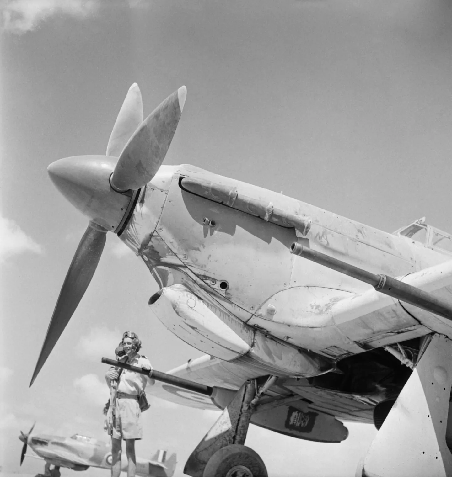 Pilot standing beside a Hurricane with a large anti-tank cannon below its wing.