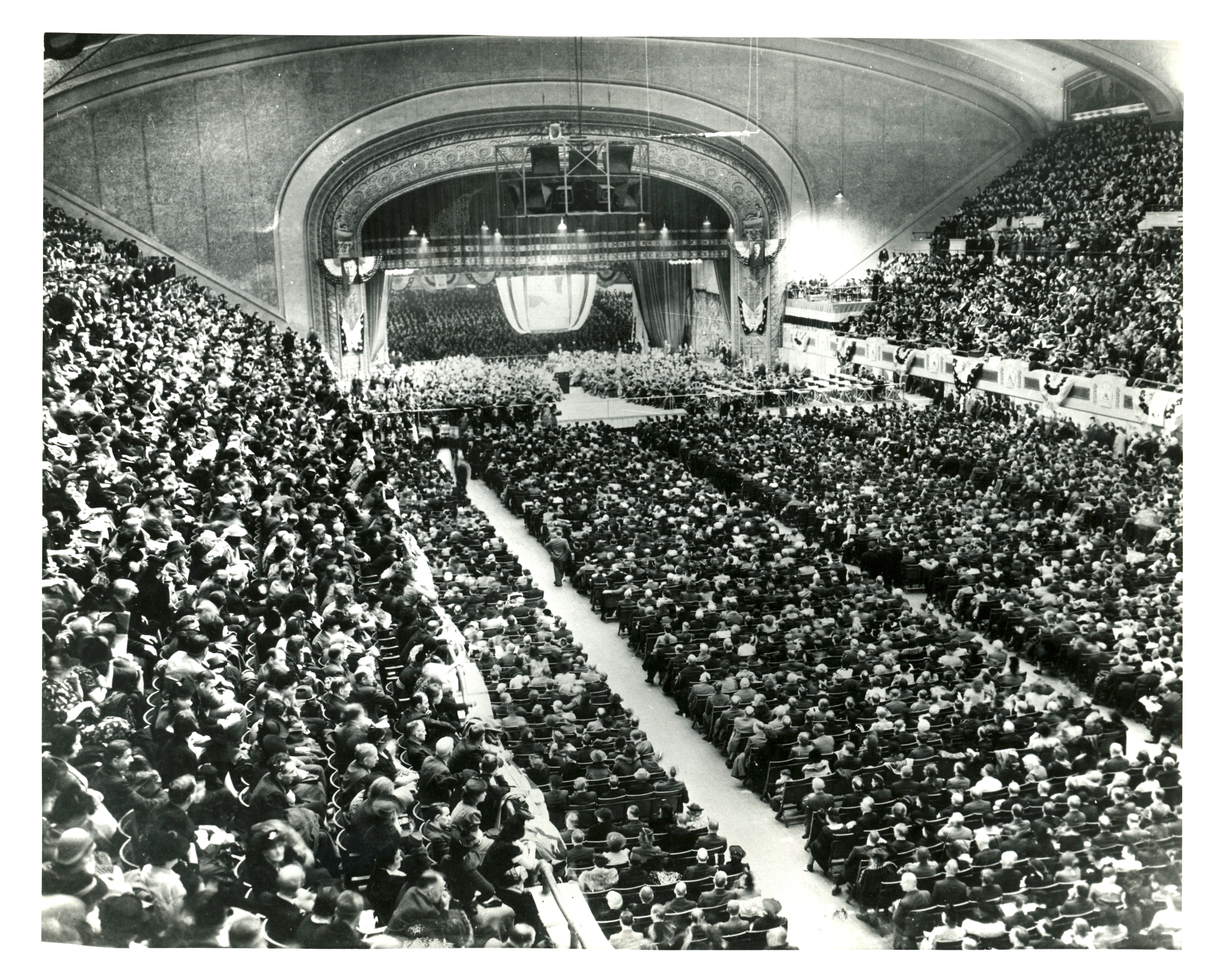 A packed auditorium with spectators filling the floor and balconies.