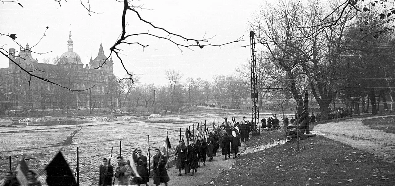 A long procession of women carrying flags near Heroes’ Square in winter.