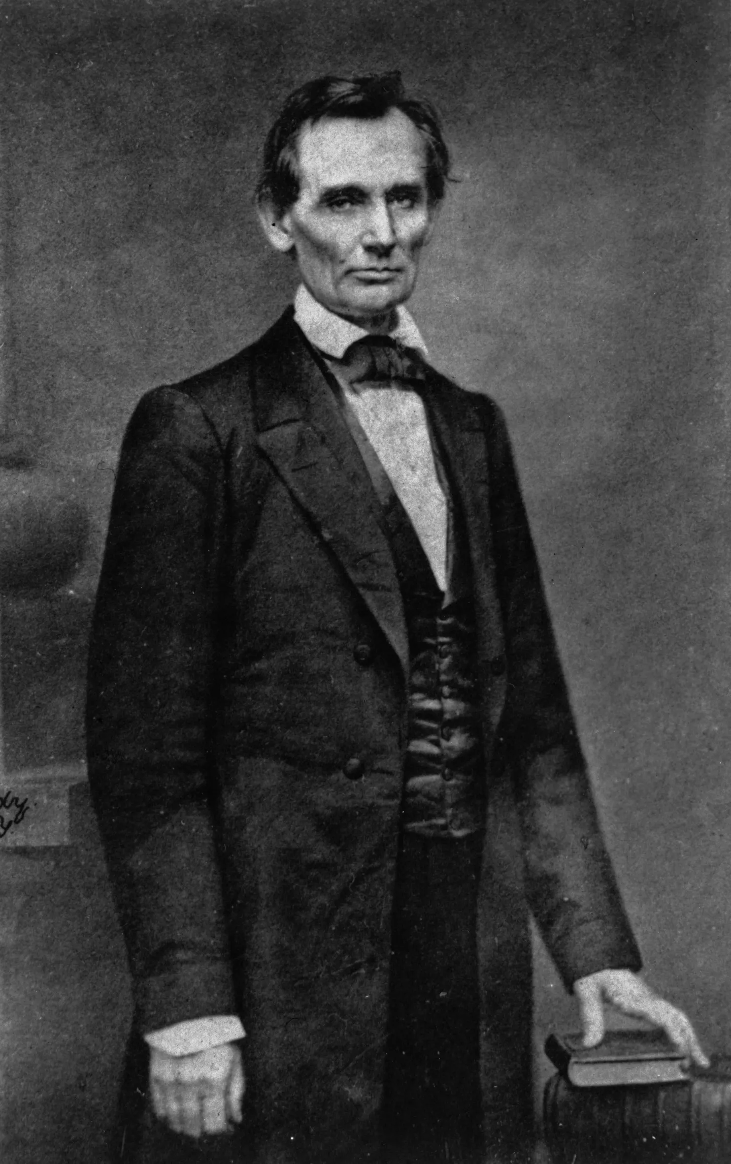 Beardless Abraham Lincoln standing beside a table in Mathew Brady’s studio.