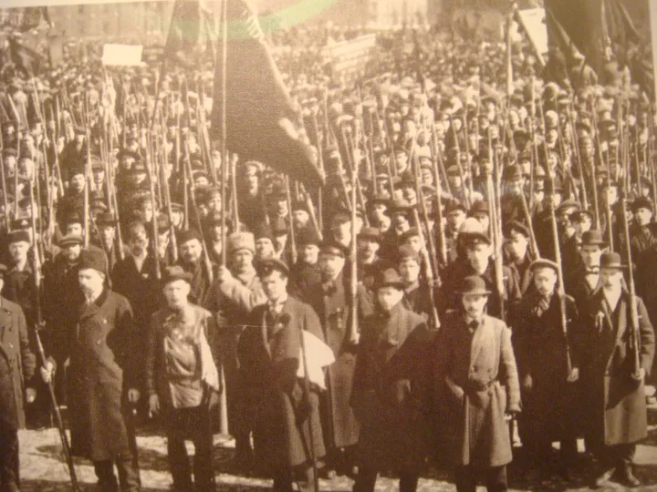 An armed Red Guard formation fills a Petrograd street, with rifles among uniforms and civilian clothing.