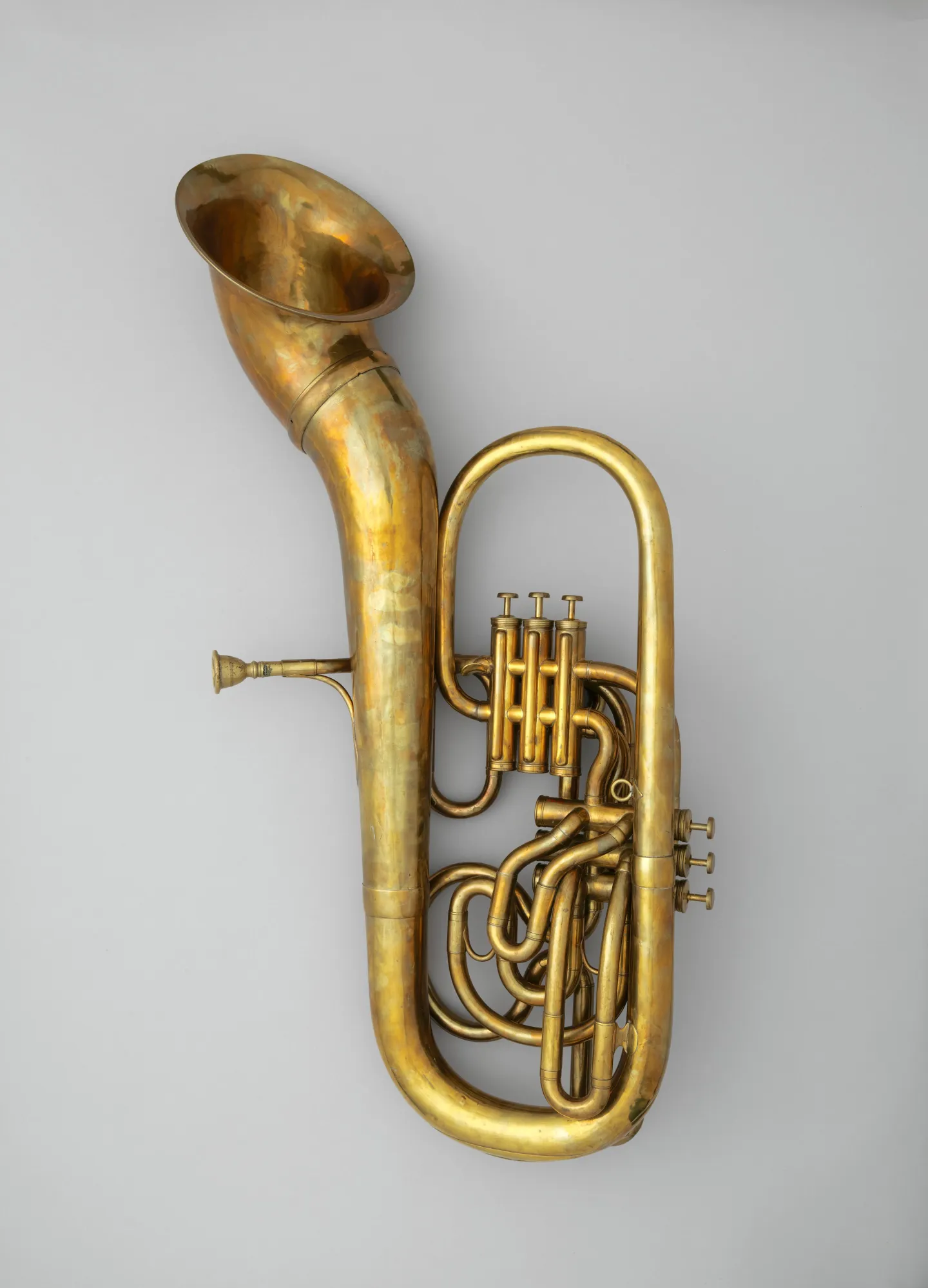 Large brass bass saxhorn with coiled tubing, six valves and a flared bell.