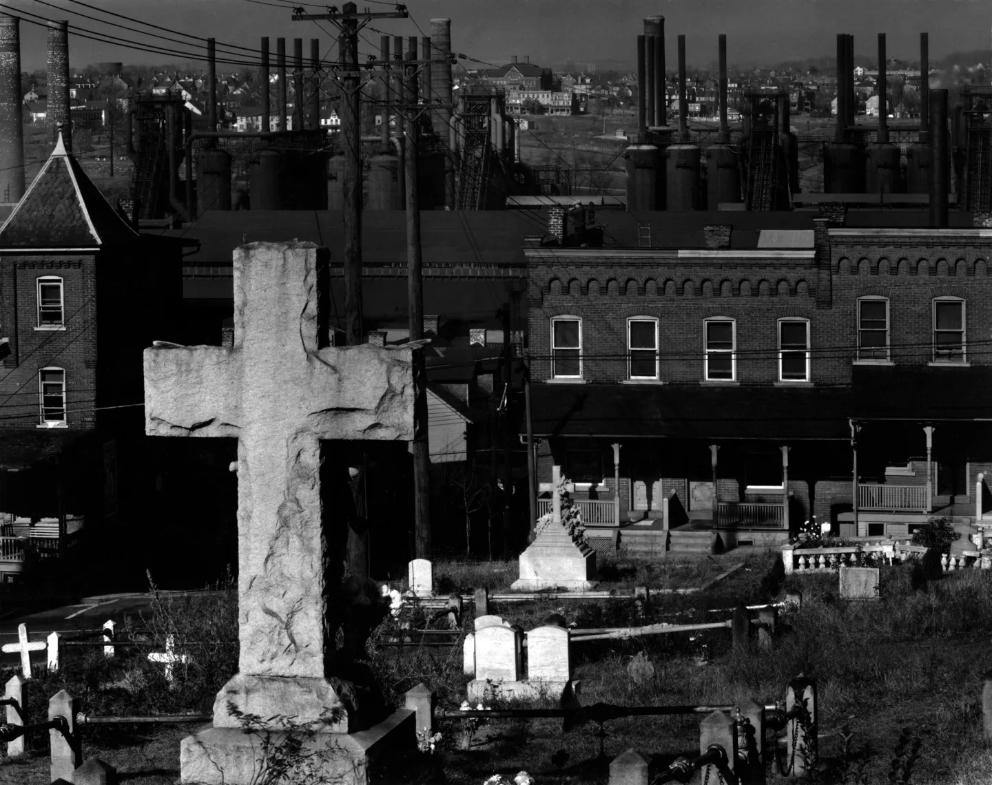 Cemetery crosses and gravestones in front of Bethlehem houses and a steel mill.