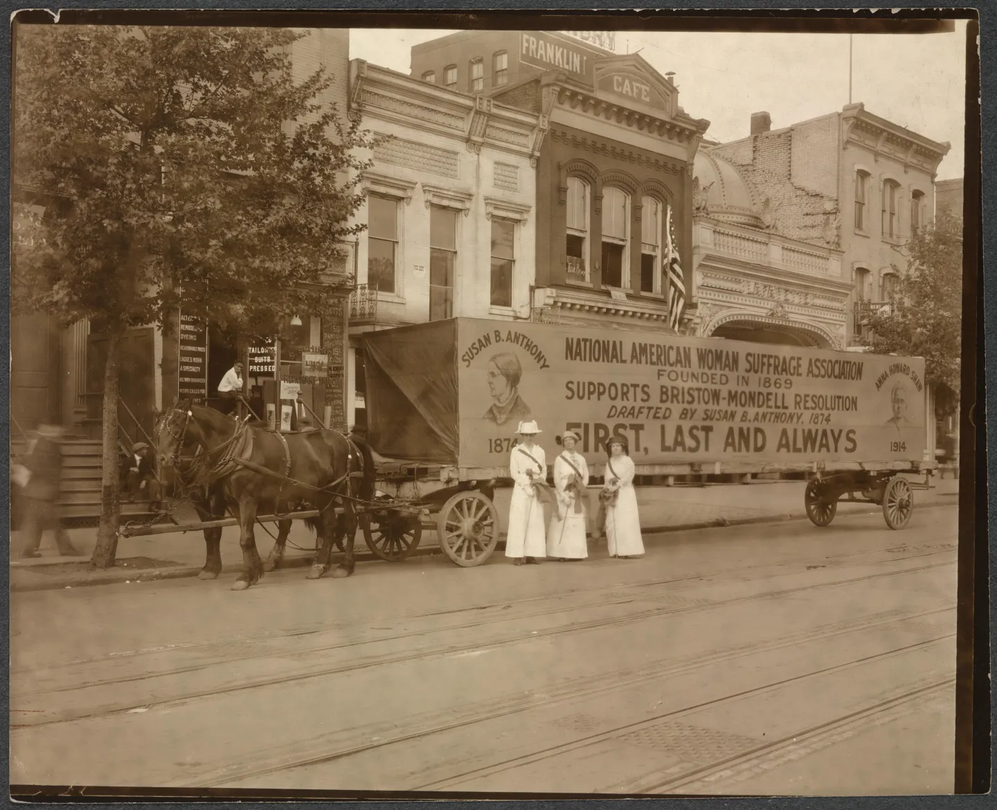 Three women beside a horse-drawn wagon carrying a large sign for a federal suffrage amendment.