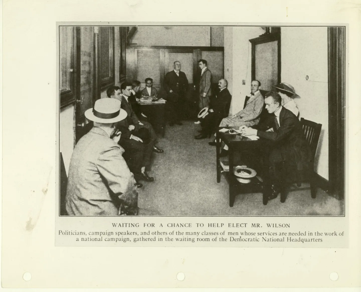Men waiting on chairs in a corridor or waiting room at Democratic campaign headquarters.