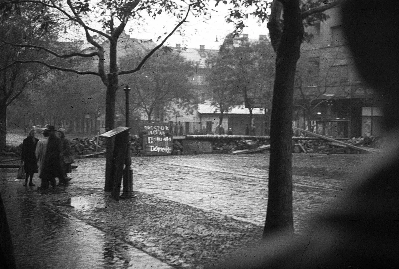 Hungarian civilians walking near a makeshift street barricade on Fehérvári Road in Budapest in 1956
