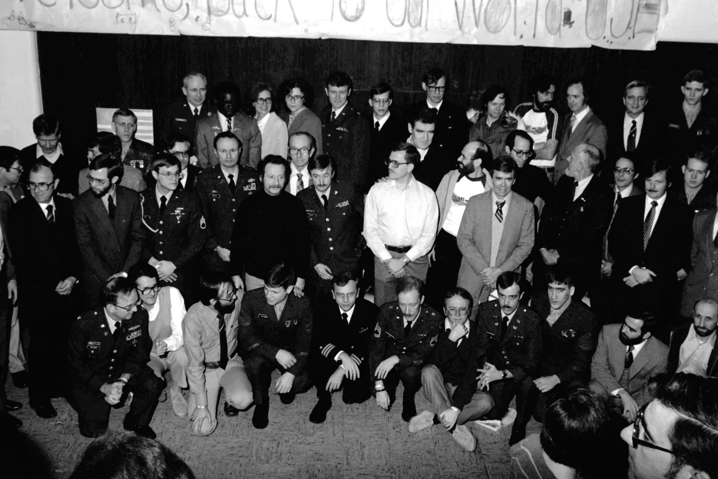 Former American hostages arranged for a group photograph beneath a welcome banner.