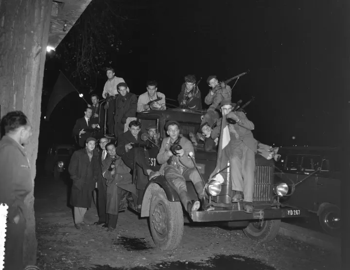 Armed Hungarian revolutionaries on and around a truck at night.