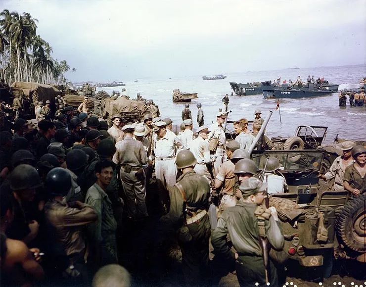 MacArthur and other officers surrounded by troops, vehicles and landing craft on a crowded Leyte beachhead.