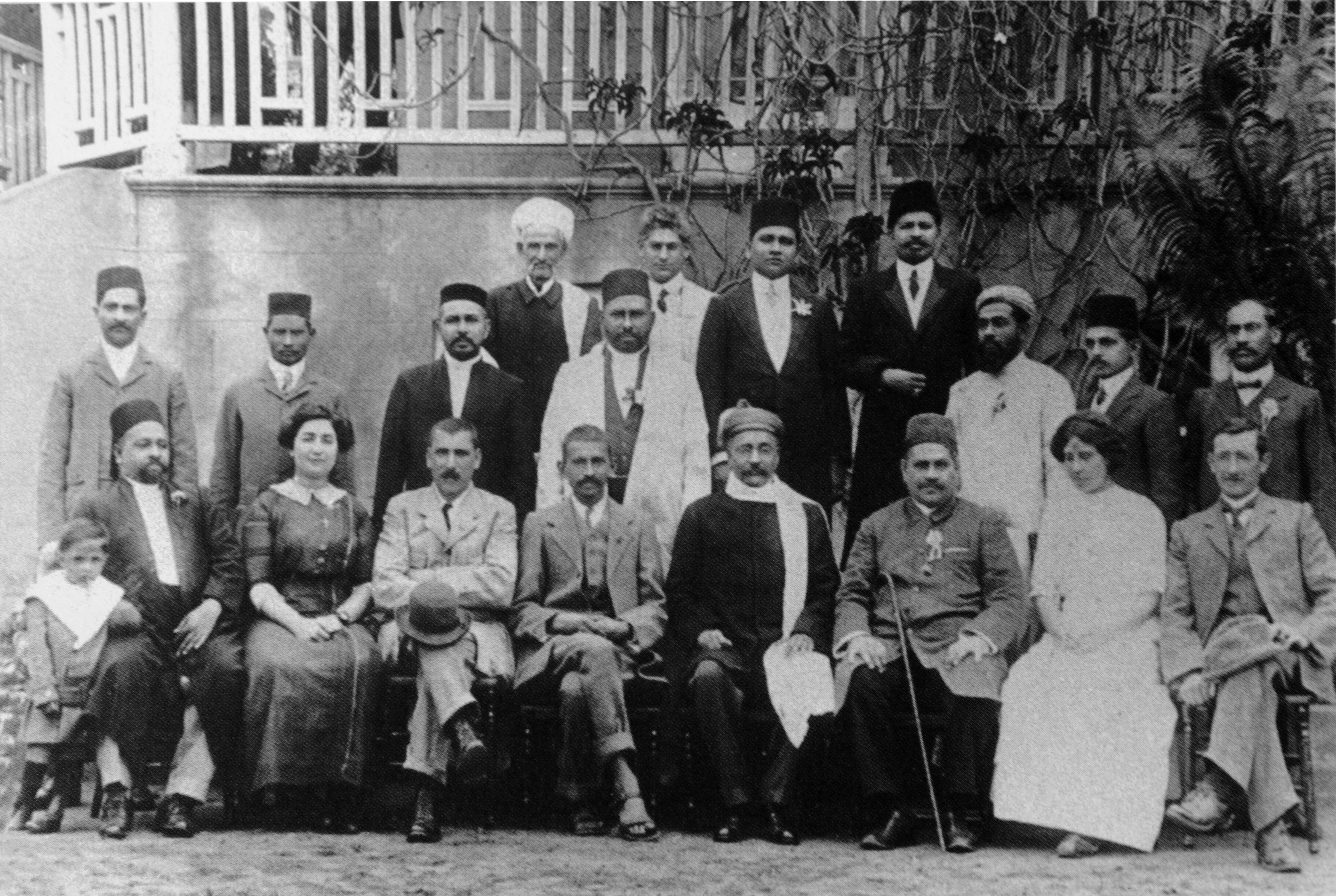 Group portrait of Gandhi, Gokhale and supporters seated and standing outside a building.
