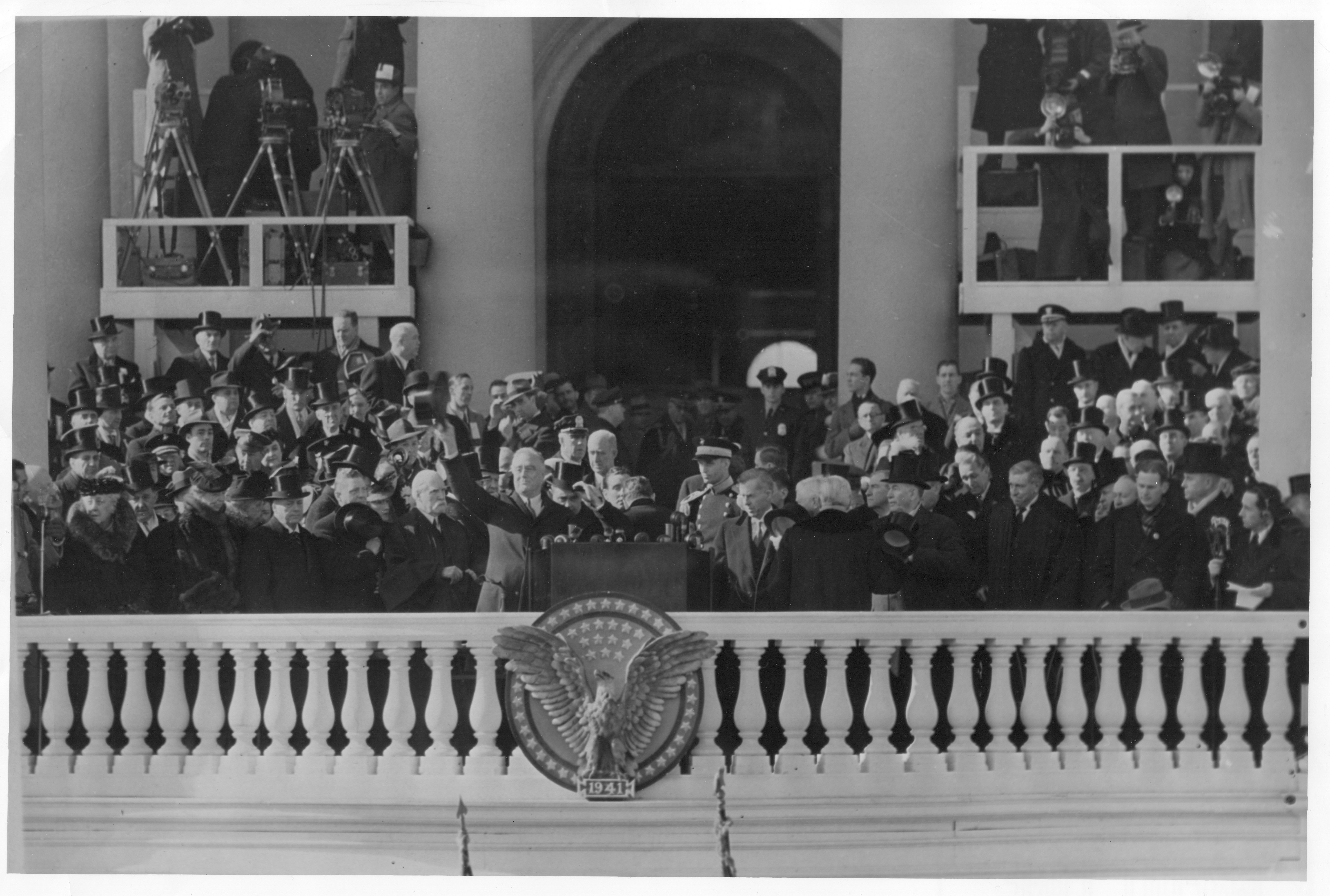 Roosevelt waving from the inaugural platform amid officials and spectators.